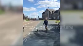 Shocking video shows a man cycling round a busy roundabout - alongside a DOG on a lead