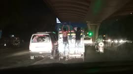 Two boys cling dangerously to the back of a transport vehicle in the Indian capital
