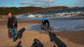 Welsh  Grannies mobility scooter nearly engulfed with surfer beach waves