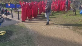 People in red costumes walk through Vauxhall park during Extinction Rebellion protest