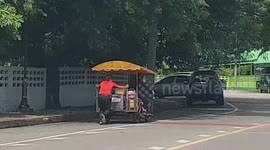 Kind-hearted postman pushes exhausted food vendor on her broken cart in Thailand