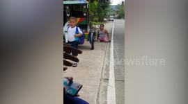 Caring schoolboy carries plastic chair to help disabled mother climb onto bus in the Philippines