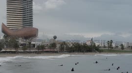 slow motion shot of barcelona's beaches with large waves and surfers out in the sea