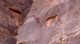 Barefoot rock climber repels down the side of a giant rock in Zion National Park, Utah