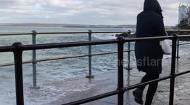 Pedestrians dodge crashing waves in St Ives, Cornwall