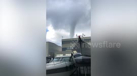 Huge waterspout towers above moored boats on the coast of Italy