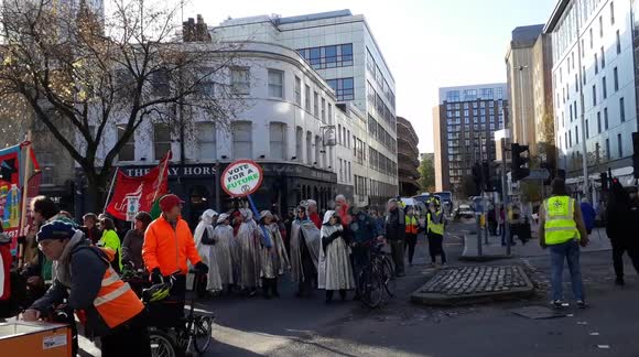 Climate change protesters in costume line the streets of Bristol rallying against climate change and Black Friday consumerism, holding up traffic