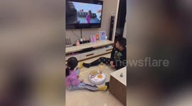 Creative father and daughter use robot vacuum to serve snacks and drink while watching TV together in China