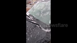Man satisfyingly scraping ice off windshield