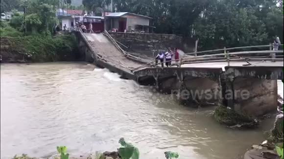 Residents in Indonesia forced to use collapsed bridge after heavy rain wreaks havoc