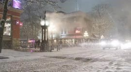 Cars driving in heavy snow in front of Gastown Steam Clock