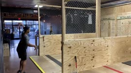 Axe thrower gets bullseye trick shot while riding longboard