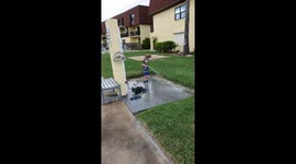 Toddler soaking Dad with hose on holiday