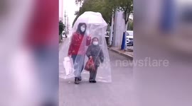 Chinese mother and daughter walk on street covered in huge plastic bag amid coronavirus outbreak