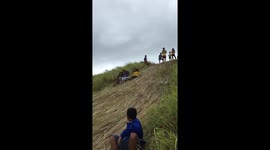 Teenagers slide down grassy hill in the Philippines