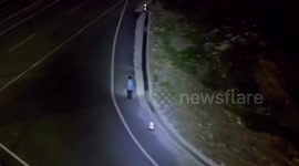 Chinese police officer lights up road using patrol drone for pedestrian walking along at night