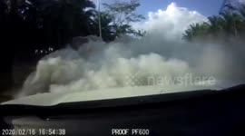 Dust swallows upcoming car after bags of cement falling from truck in Thailand