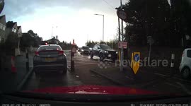 Car comes around fast around a bend and traffic moving slowly at temporary lights cuts in front of a van trying to get through bollards