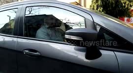 Car driver casually sits in his vehicle while being towed away by removal truck