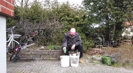 Bearded man in dirty clothes pours liqour and beer in a bucket