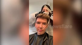 UK student gets hair cuit by hairdresser in hazmat suit