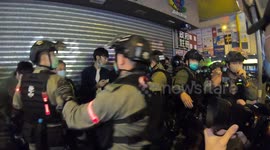 Riot police line five bystanders against wall for identity check during protest in Hong Kong