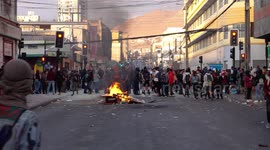 People protesting in the streets, some of them steal things from the super market