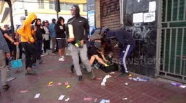People protesting in the streets, some of them steal things from the super market