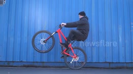 Cool Man doing Wheelie on Mountainbike next to blue steel wall