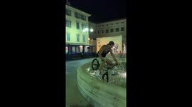Man on a bike tries stunt and falls in a fountain