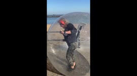 Woman self isolating exercising in a zorb ball is antagonised by walker by