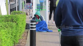 Poor Homeless Man sits next to very long queue ASDA Supermarket during Coronavirus Covid 19