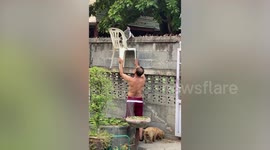 Kindhearted Thai man helps cat come down from wall with chair