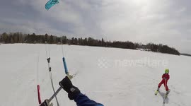 Father pulls son along while kite skiing on frozen lake in Canada