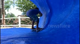 lockdown: sisters in the city of Padang playing surfing using a skate board and blue tarpaulin