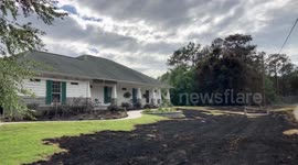 House survives at the edge of the fire with yard burnt to front door