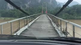 Driver travels across rickety old wooden bridge in Vietnam