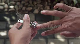 Man Cutting His Long Nails With Clipper In The Backyard