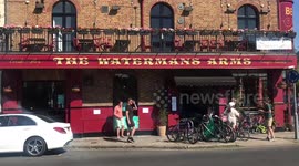Londoners enjoying takeout drinks from Thameside pub in Barnes