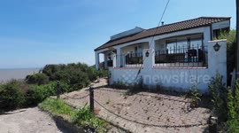 House hanging over cliff edge, Eastchurch, UK