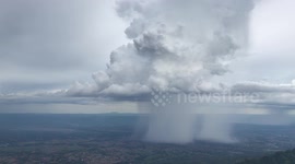 Spectacular moment four different clouds all pour with rain over mountain valley