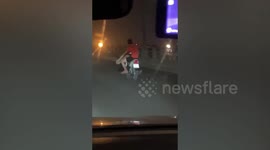 Chilled-out motorcyclist rides cross-legged on highway in Vietnam