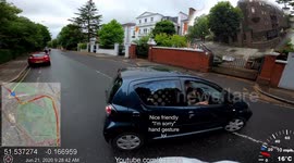 Car pulls out from side road in front of cyclist in wet conditions with i don't care gesture