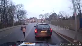 Woman walks carelessly down middle of a busy road in Poland