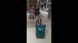 adorable and cute action of 3 year old veiled girl while shopping at the supermarket by pulling green shopping basket