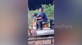 Dog helps owner on backhoe doing construction work