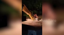 Stranded resident carried to safety in a digger as floods hit Indonesia