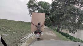 Do motorcycles and multitasking mix? For this man carrying plywood sheet, it sure does!