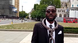 A man clad in chains protests under Churchill's statue, demanding justice over unlawful killing of his father by police