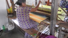 Woman weaving cloth using weaving machine at a local weaving mill run by the government Sri Lanka.